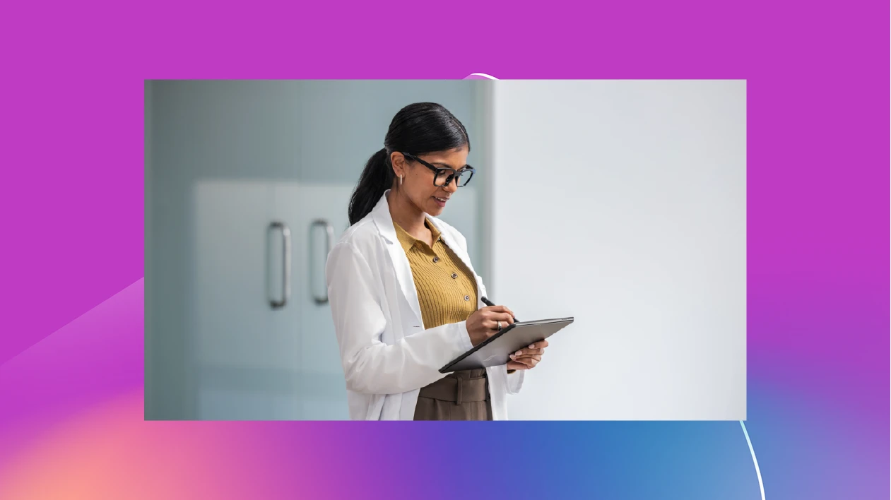 A scientist in a white lab coat writes on a tablet