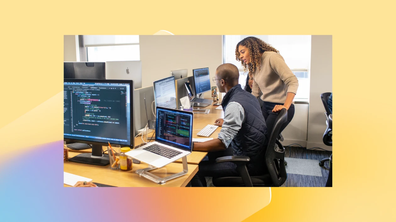 Two employees gather around a computer