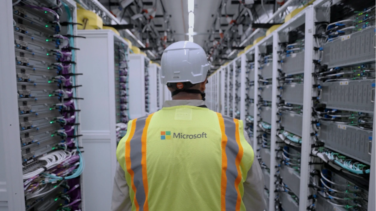 An employee standing between server racks at a Microsoft AI datacenter